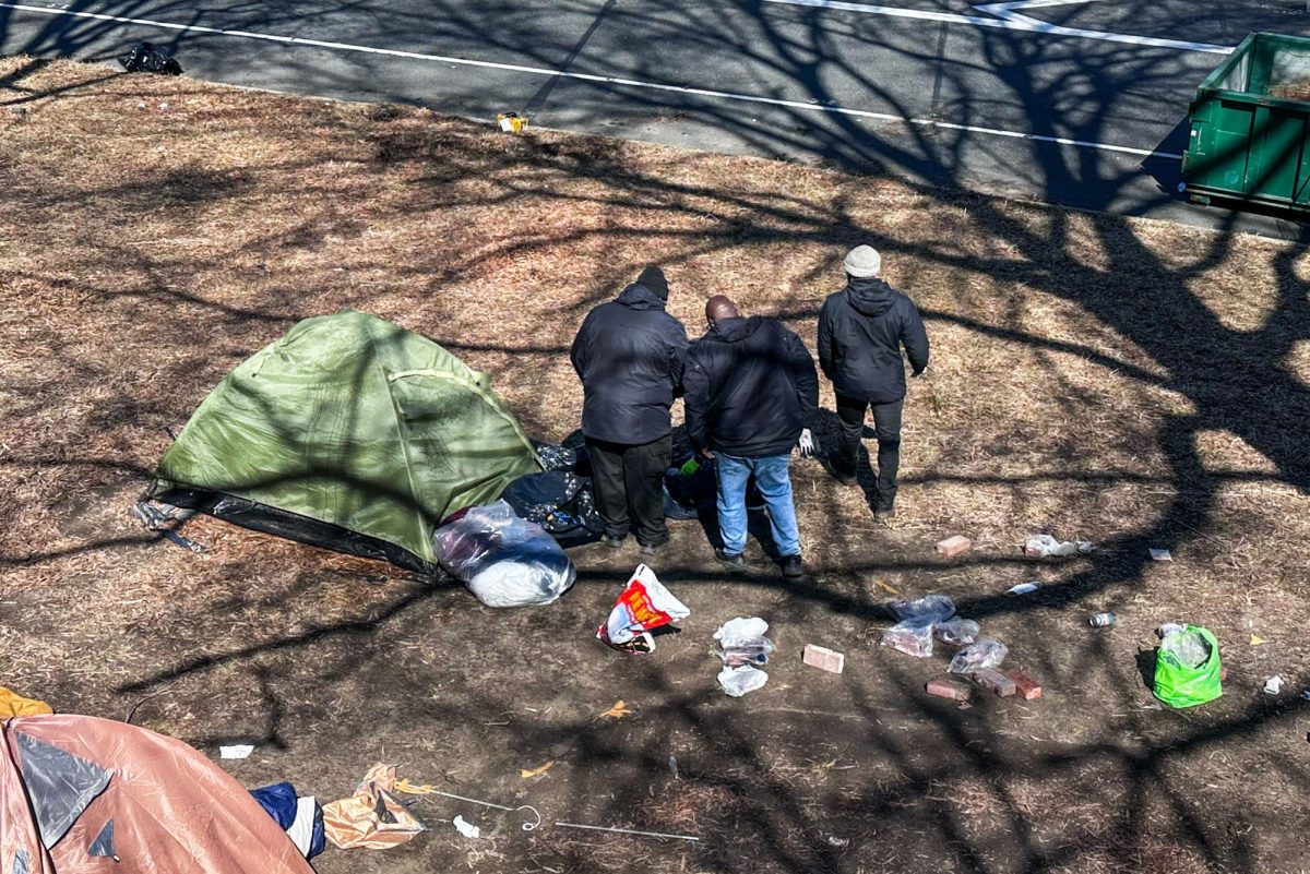 Workers clear a homeless encampment along the E Street Expressway.