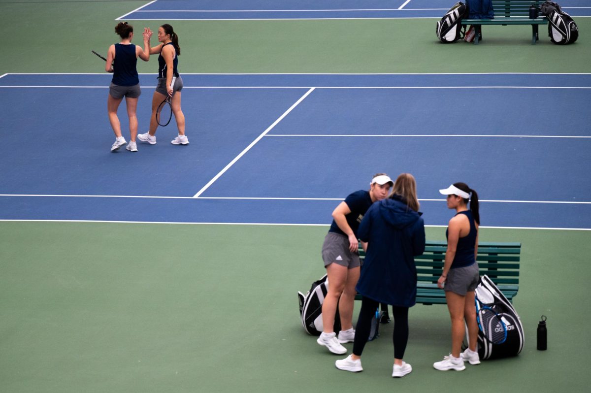 GW tennis players talk during a match against Navy in February.
